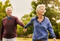 elderly couple walking in field of grass