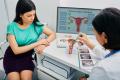 Gynecologist showing an anatomical model of the uterus during a consultation with a female patient for vaginal rejuvenation.