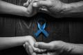 Image of hands clasped around a blue ribbon representing mourning for prostate cancer.