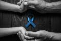 Image of hands clasped around a blue ribbon representing mourning for prostate cancer.