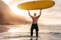 Man on TRT Therapy holding up a surfboard