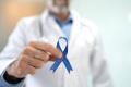 A doctor holding a blue ribbon for prostate cancer.