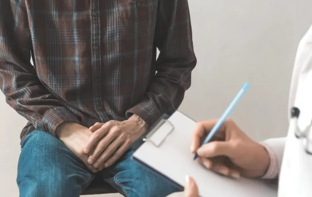 a doctor takes notes on their clipboard while a male patient sits