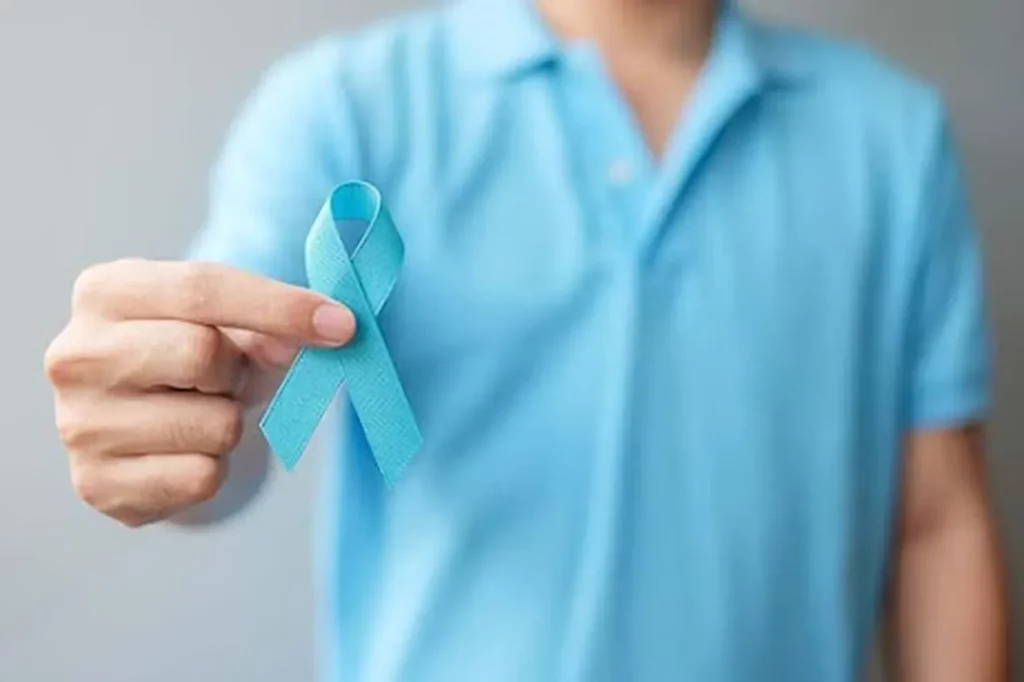 a man wearing a blue collared shirt holding up a blue ribbon for prostate cancer
