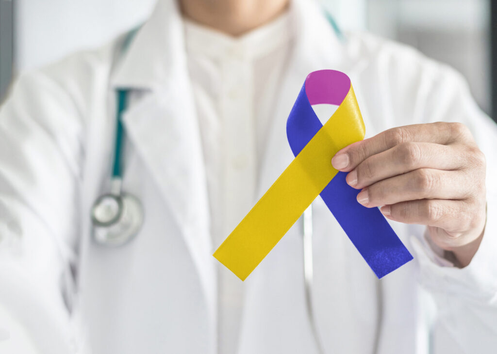 a doctor wearing a white lab coat holding up a blue, purple, and navy blue ribbon that represents bladder cancer