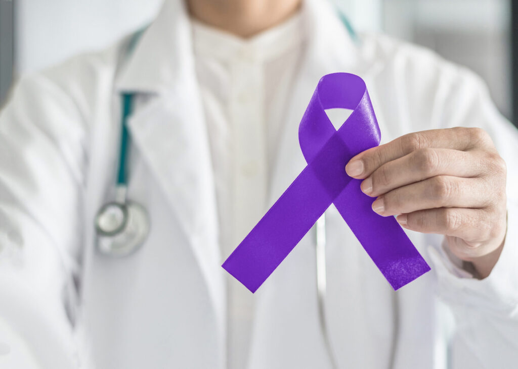 male doctor holding up purple cancer ribbon for testicular cancer