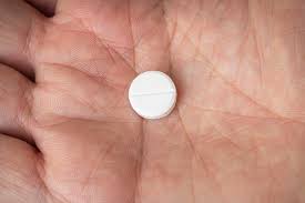 a clomid (clomiphene citrate) pill in a man's hand.